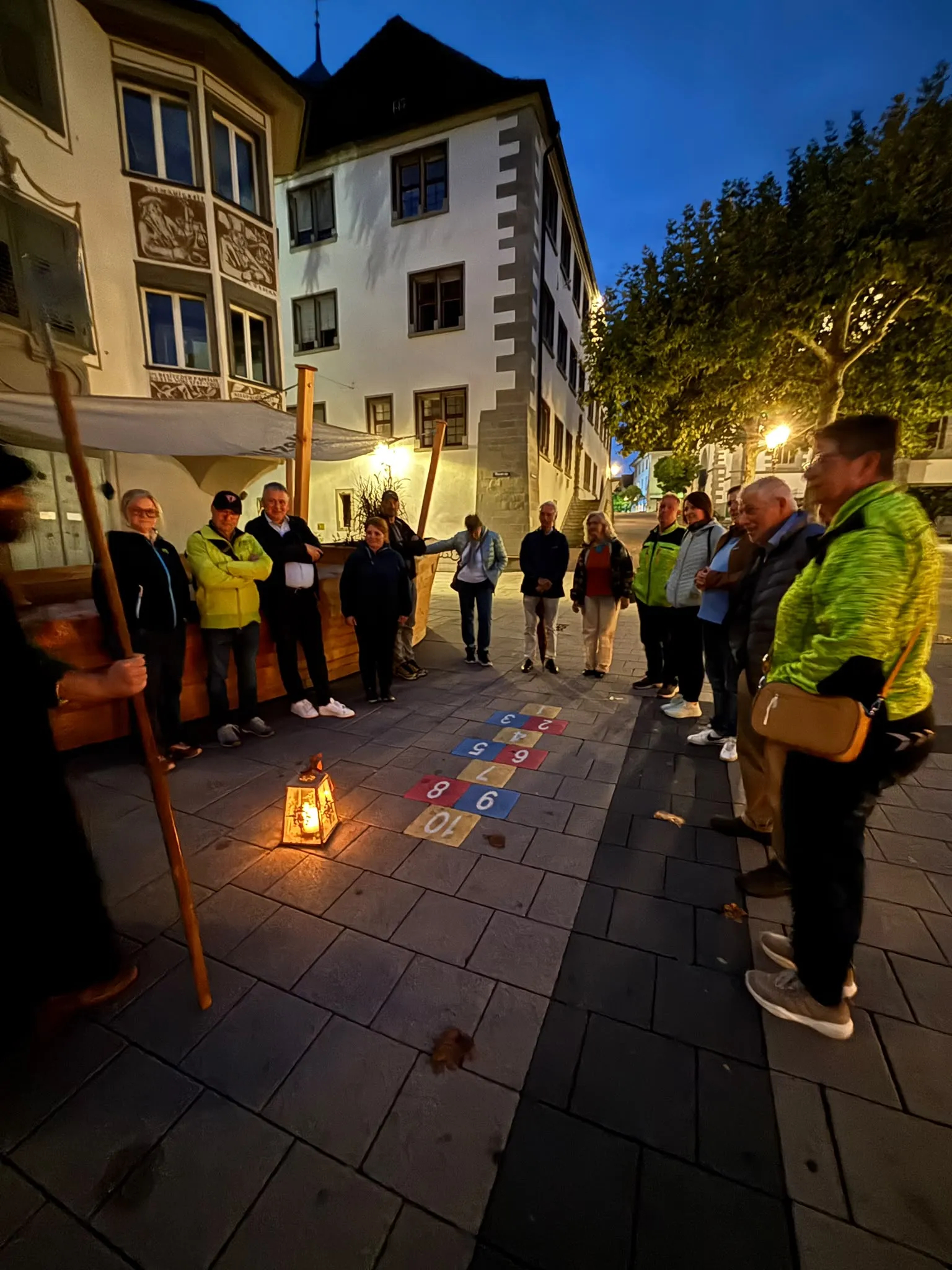 Die Gruppe steht im Kreis um die Laterne auf einem Platz in der Altstadt