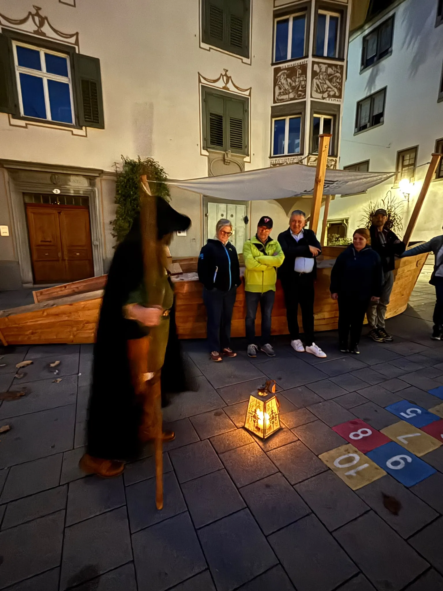 Der Nachtwächter unterwegs vor historischen Häuserfassaden, die Laterne leuchtet auf dem Pflaster