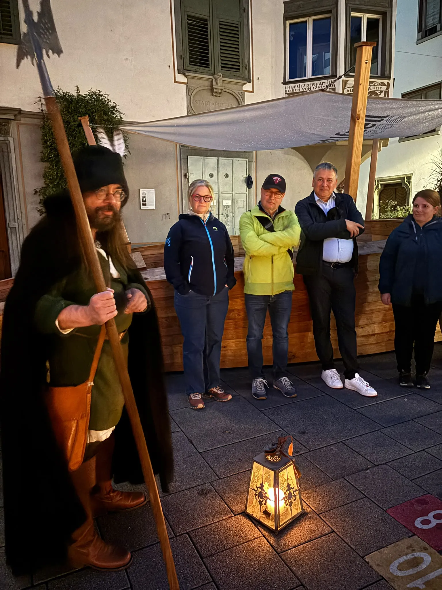 Der Nachtwächter in historischer Gewandung mit Hellebarde erzählt der Gruppe von der Stadtgeschichte